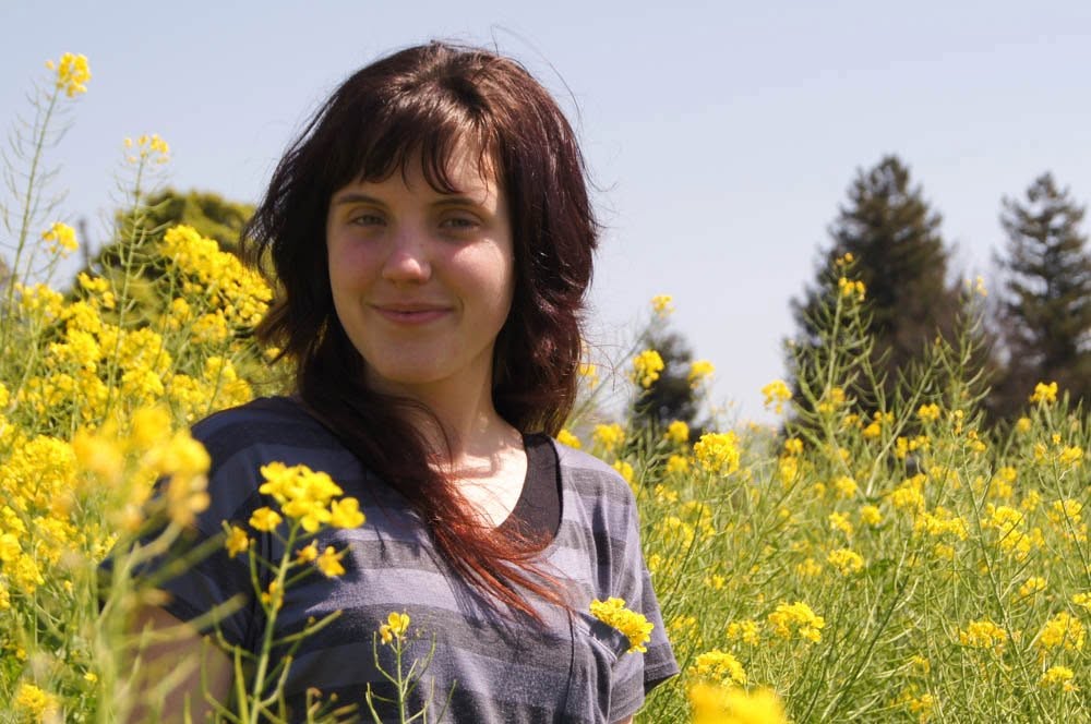 Janelle smiling in a field of yellow wildflowers